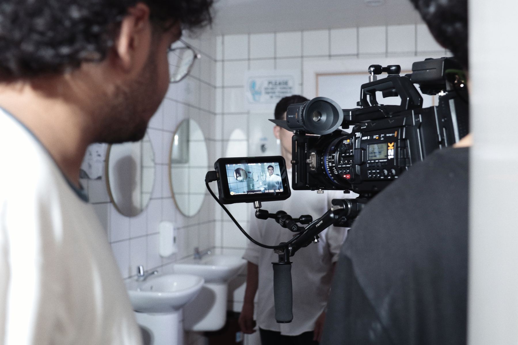 A camera operator framing a shot with a fully rigged cinema camera