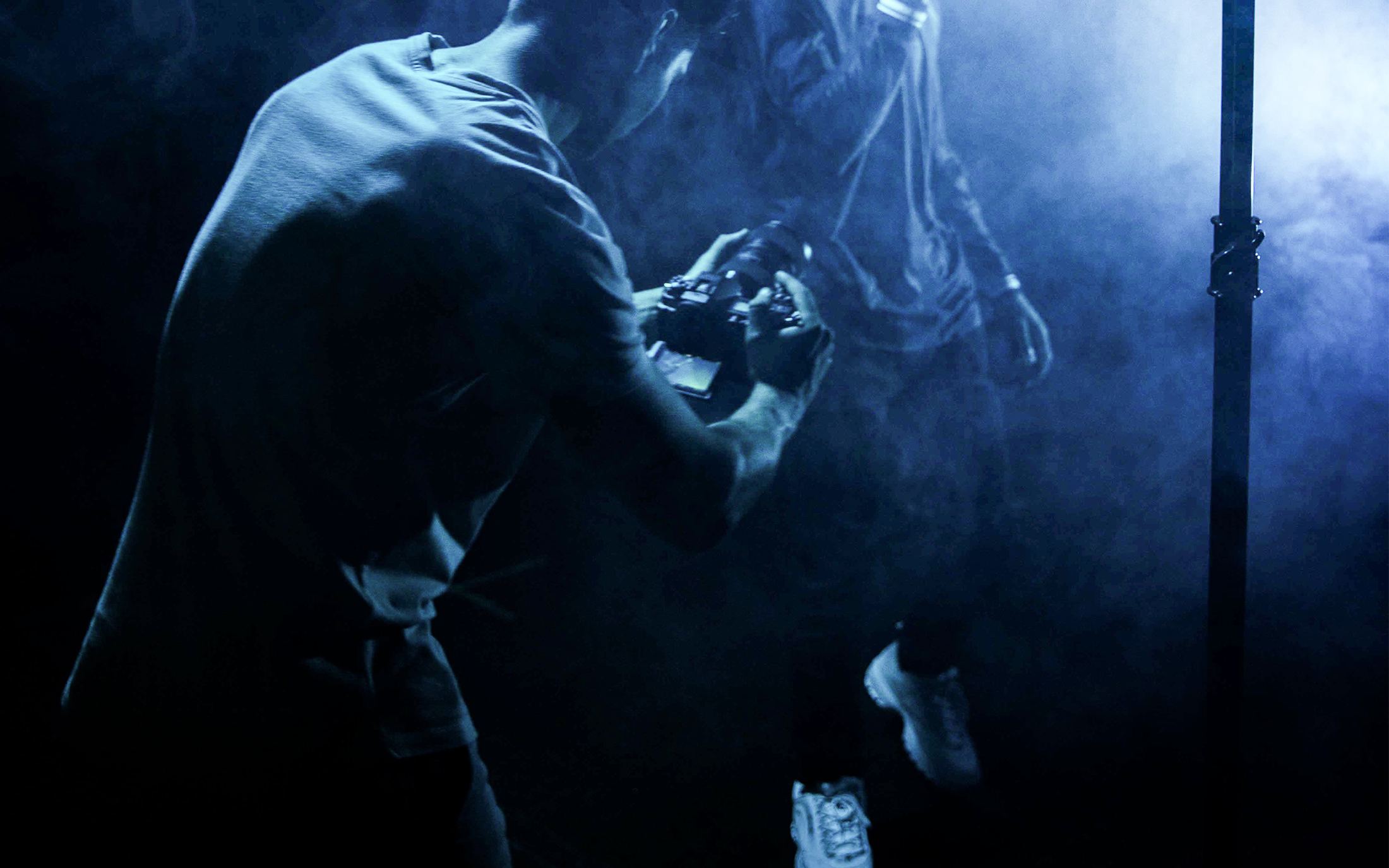 A camera operator filming in blue haze